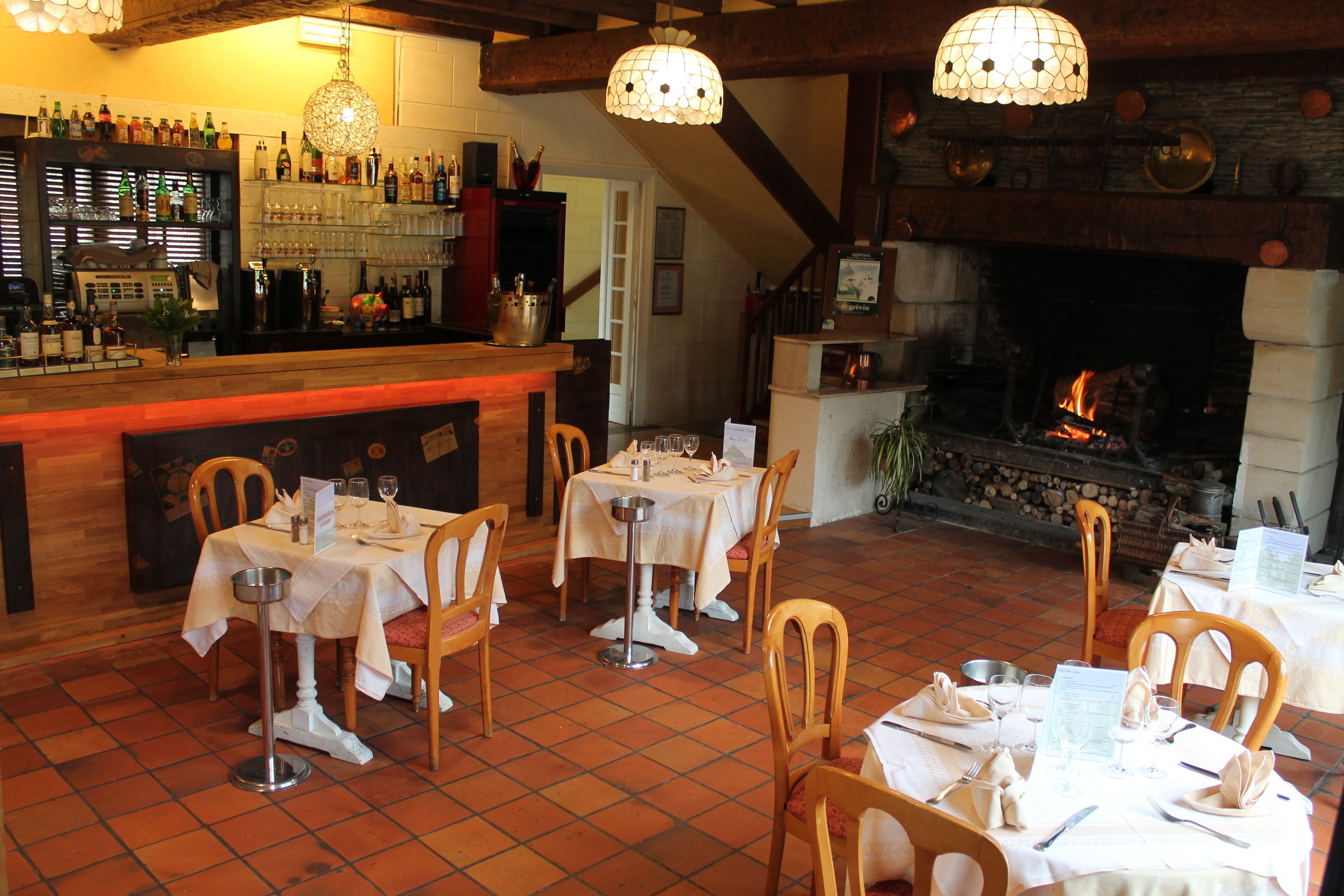 A restaurant with a bar area, tables set for dining, and a fireplace.