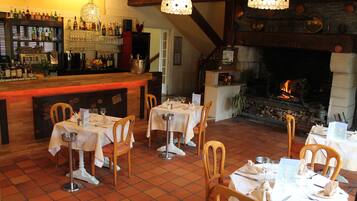 A restaurant with a bar area, tables set for dining, and a fireplace.