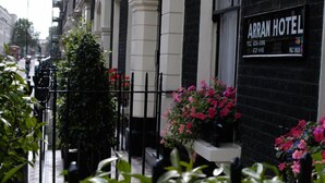 A black Arran Hotel with a white facade, a black metal fence, and potted flowers. - Arran House Hotel (London)