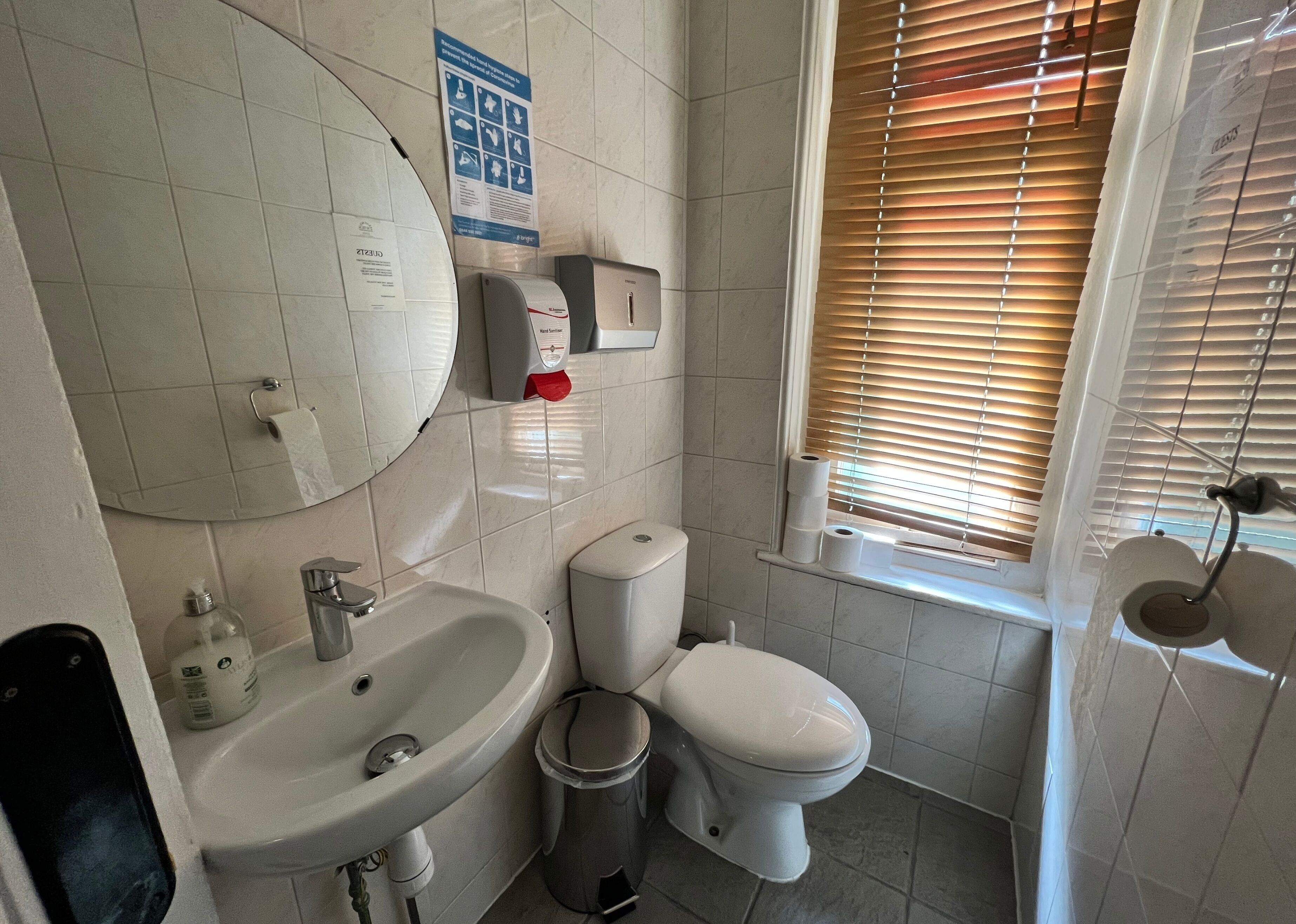 A bathroom with a sink, toilet, and window with blinds.