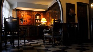 A room with a checkered floor, wooden furniture, and a lamp. - Hôtel Eychenne (Saint-Girons)