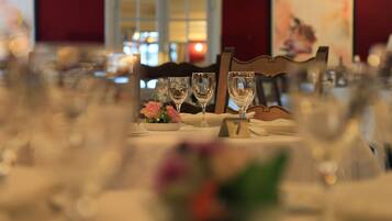 A dining table set with wine glasses, a number card, and a flower arrangement.
