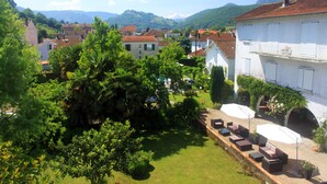 A courtyard with outdoor seating, surrounded by lush greenery and traditional architecture. - Hôtel Eychenne (Saint-Girons)
