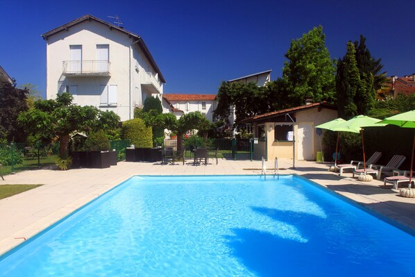 Piscine extérieure en saison, parasols, chaises longues