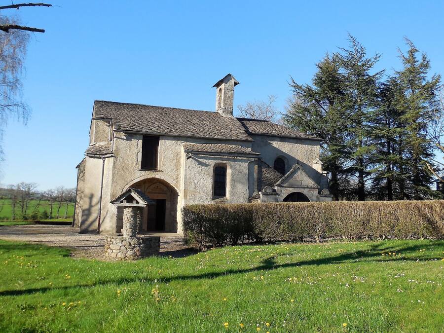 A stone building with a chimney, arched windows, and a small entrance.