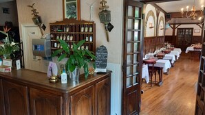 L’intérieur d’un restaurant est aménagé avec des meubles en bois, un comptoir où l’on prend les commandes, agrémenté d’une plante, et un panneau affichant le menu.