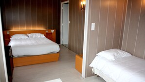 Une chambre d’hôtel avec deux lits, une tête de lit en bois et un plancher de couleur claire.