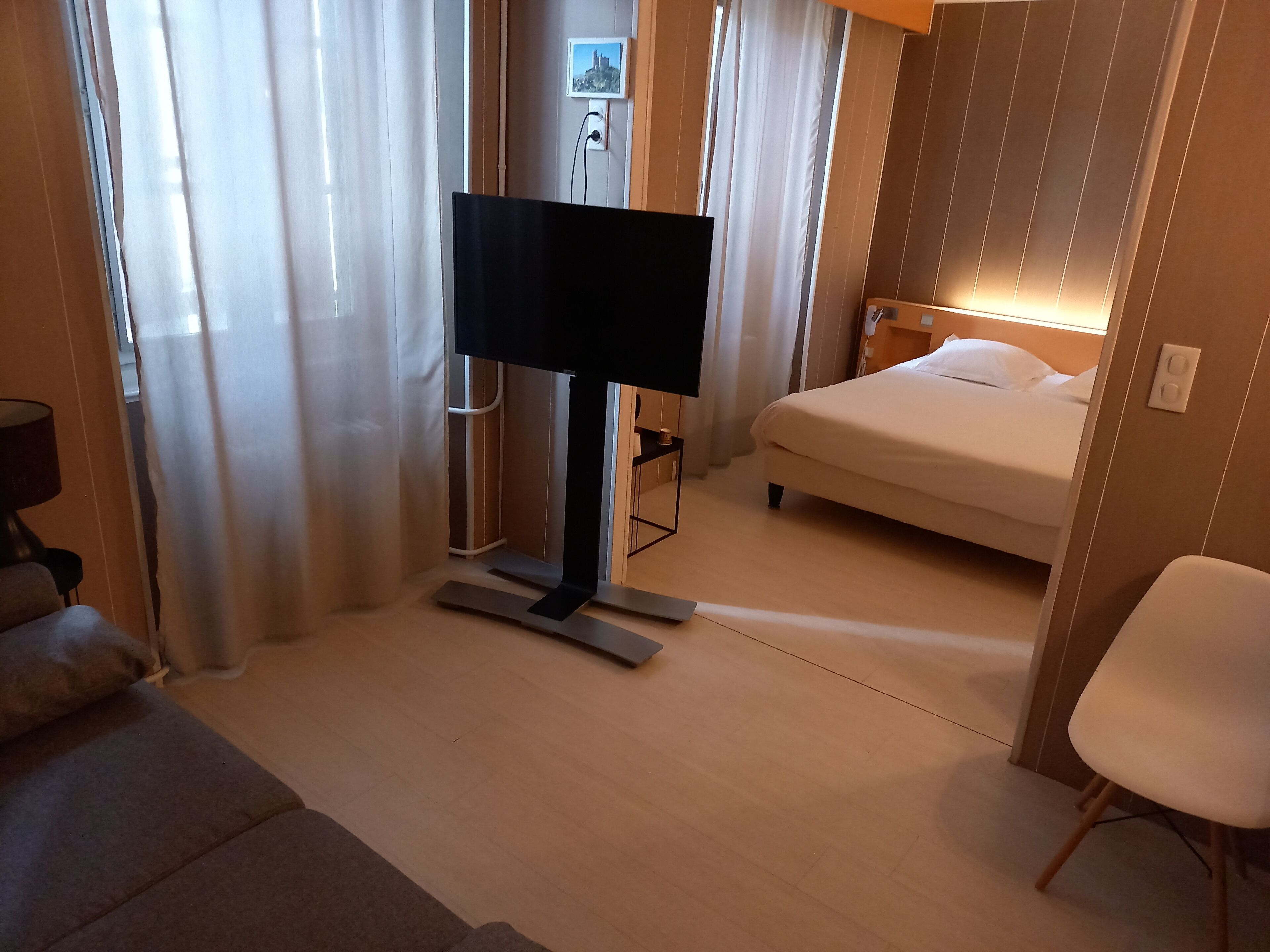 Una habitación de hotel con cama, televisión, escritorio y una silla.