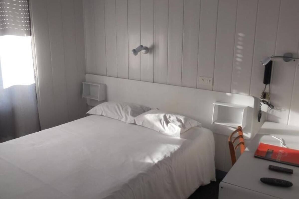 Een hotelkamer met een bed, nachtkastje en een spiegel.