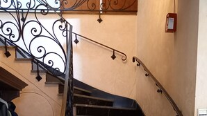 Un escalier avec des marches en marbre noir et une rampe en fer forgé.