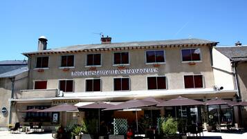 A building with a sign reading "Hotel Restaurant de Vaux-le-Vicomte" and outdoor seating with umbrellas.