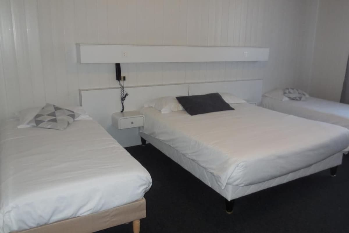 A hotel room with two single beds, a nightstand with a phone, and a headboard with a power outlet.