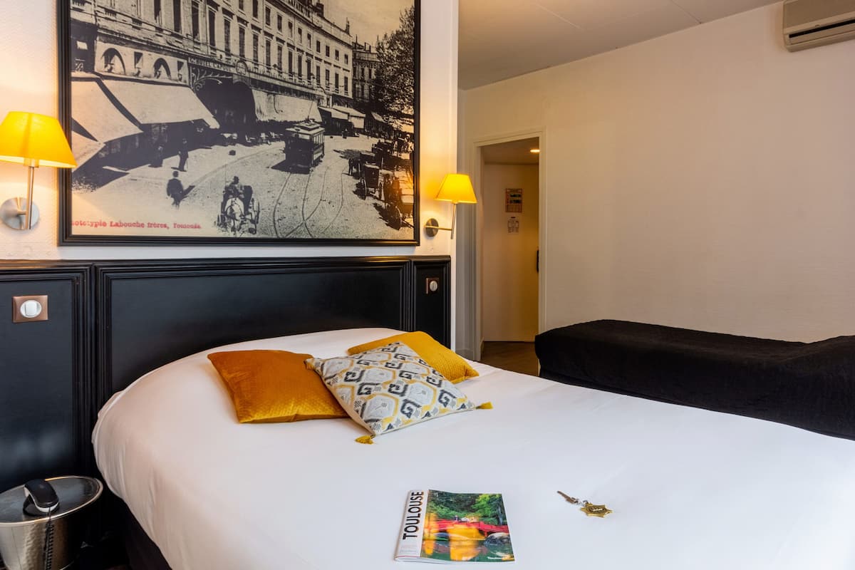 Een hotelkamer met een bed, twee lampen, een ingelijst schilderij aan de muur en een tijdschrift op het bed.