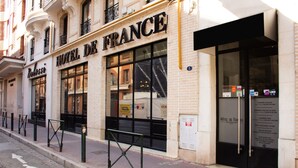 Eine Hotelscheune mit einem großen Schild, auf dem "HOTEL DE FRANCE" steht, und einer sichtbaren Eingangstür.