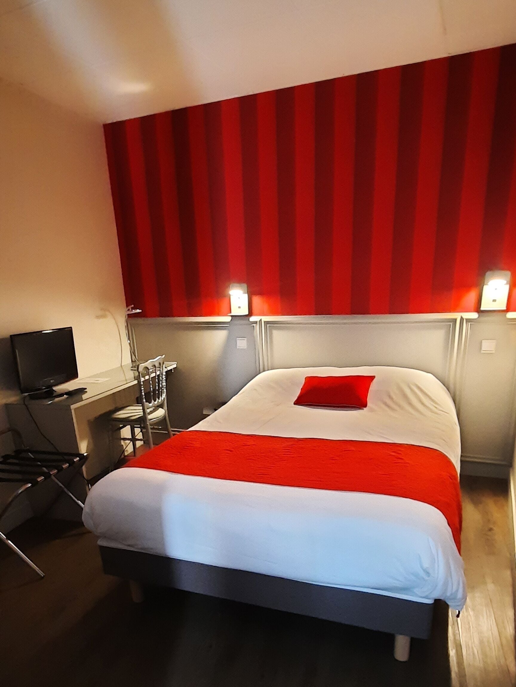 Una habitación de hotel con una cama, un escritorio y un televisor.
