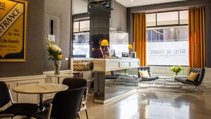 Eine Hotellobby mit Empfangstresen, Sitzgelegenheiten und einem großen Fenster mit Vorhängen.