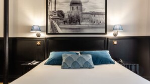 Ein Hotelzimmer mit einem großen Bett, zwei Nachttischlampen, einem Stadtbild im Bilderrahmen und einem Telefon auf dem Nachttisch.