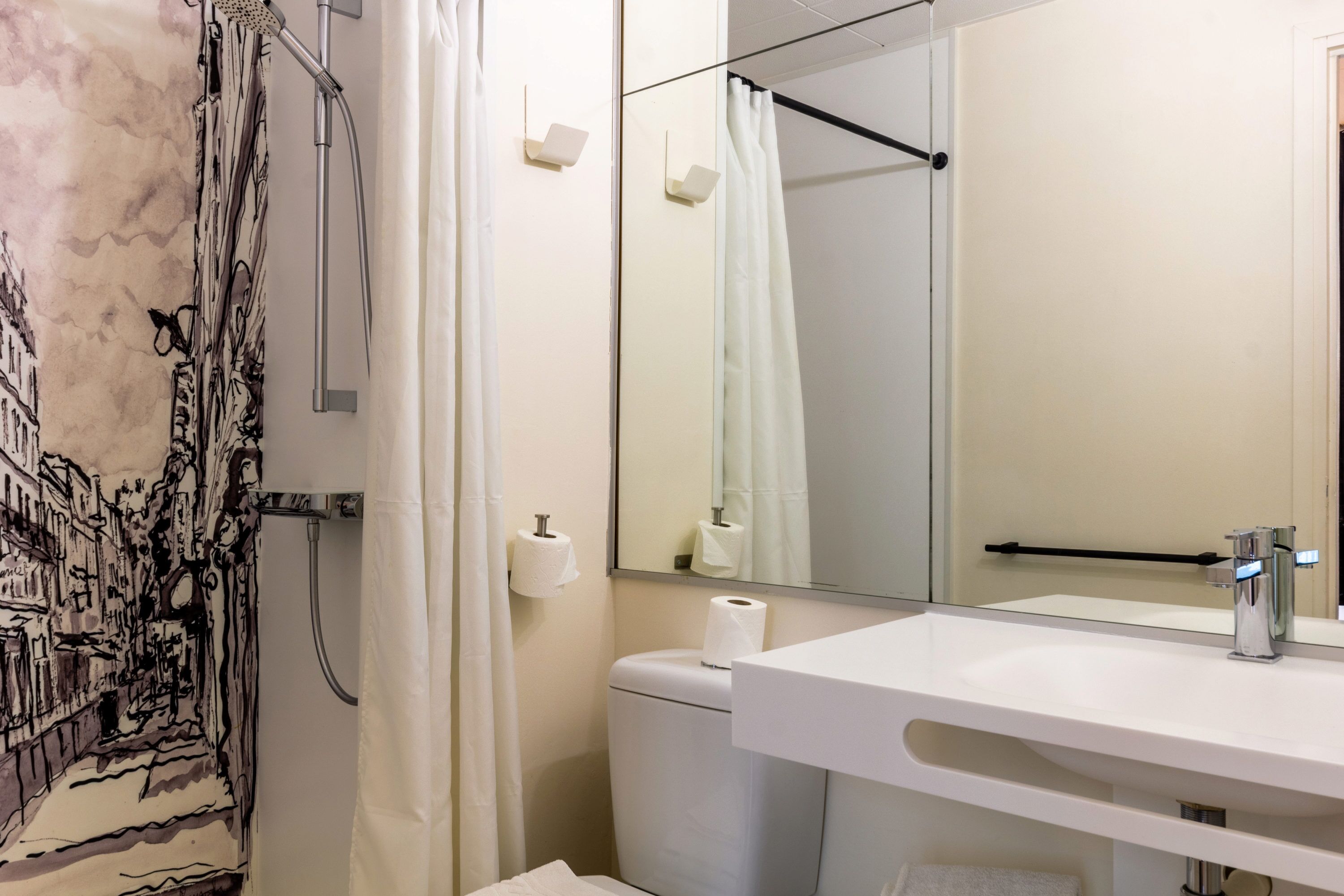 A bathroom with a shower, toilet, sink, and mirror.