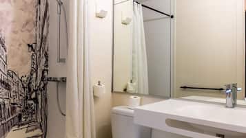 A bathroom with a shower, toilet, sink, and mirror.