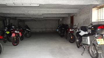 Un garaje para estacionamiento con varias motocicletas aparcadas en filas.
