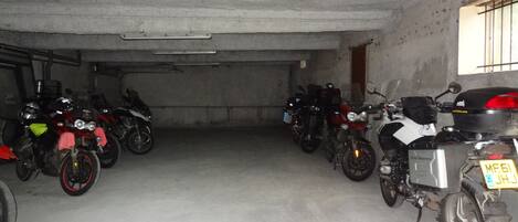 A parking garage with multiple motorcycles parked in rows.