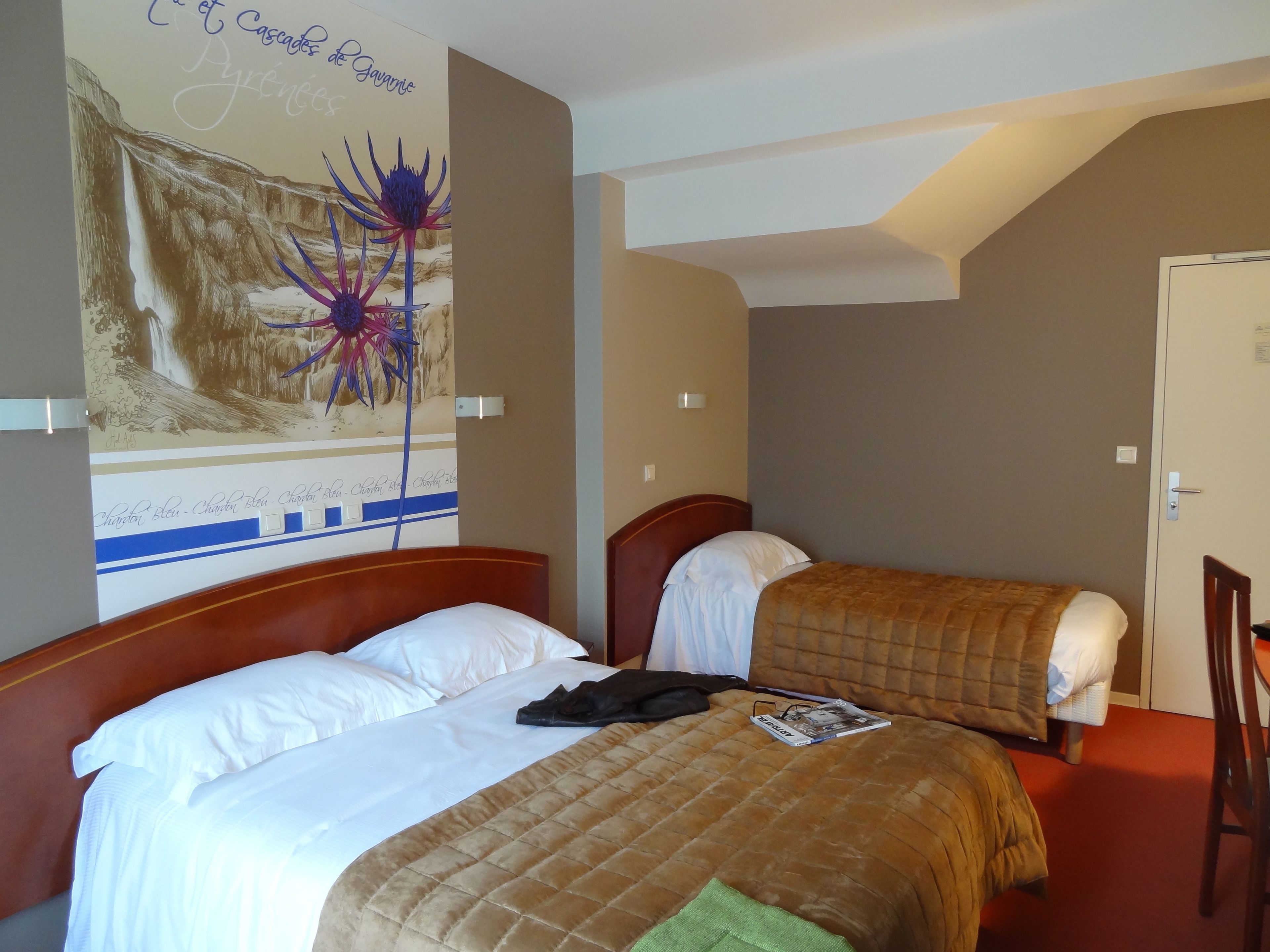 Una habitación de hotel con dos camas, un cartel grande en la pared y una puerta.