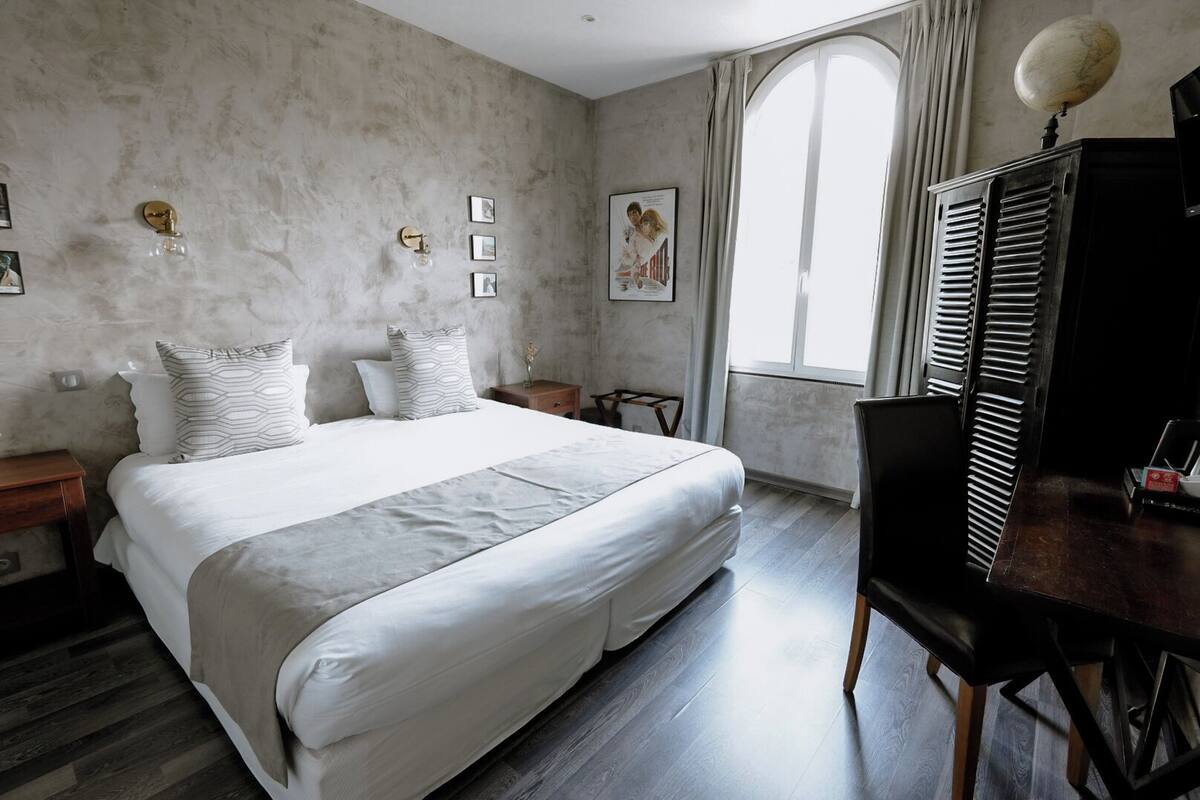 A bedroom with a large bed, a desk, and a window.