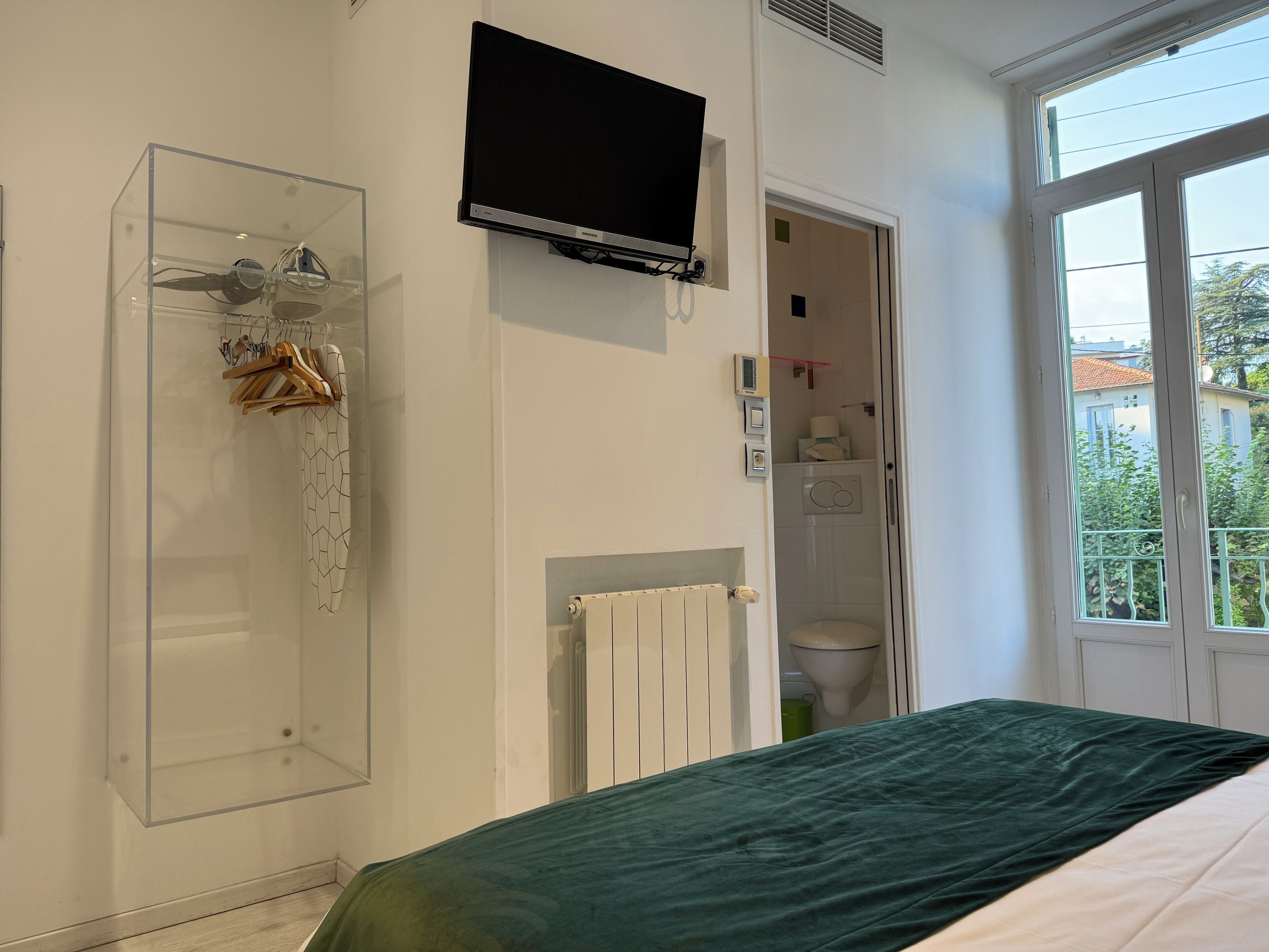 Un dormitorio con cama, ducha, inodoro y televisor.