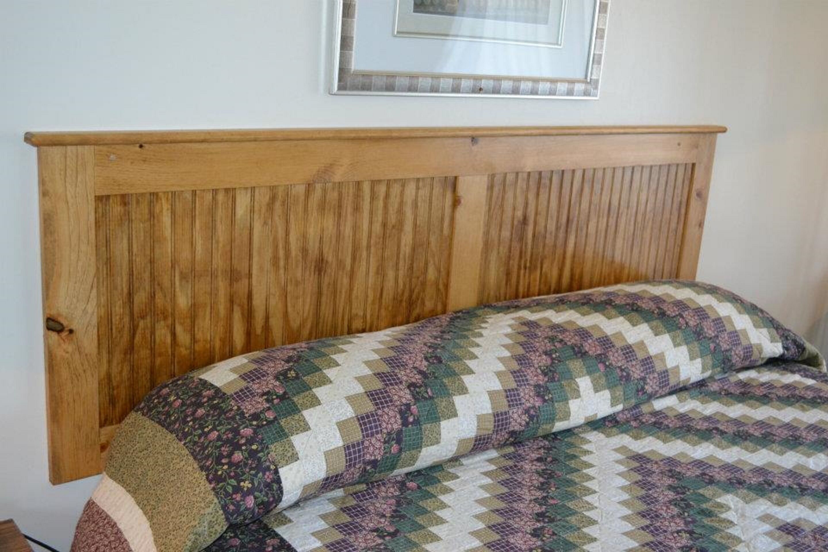 A bed with a wooden headboard and a patterned quilt.
