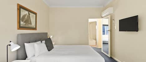 Una habitación de hotel con cama, mesita de noche, lámpara y un cuadro en la pared.