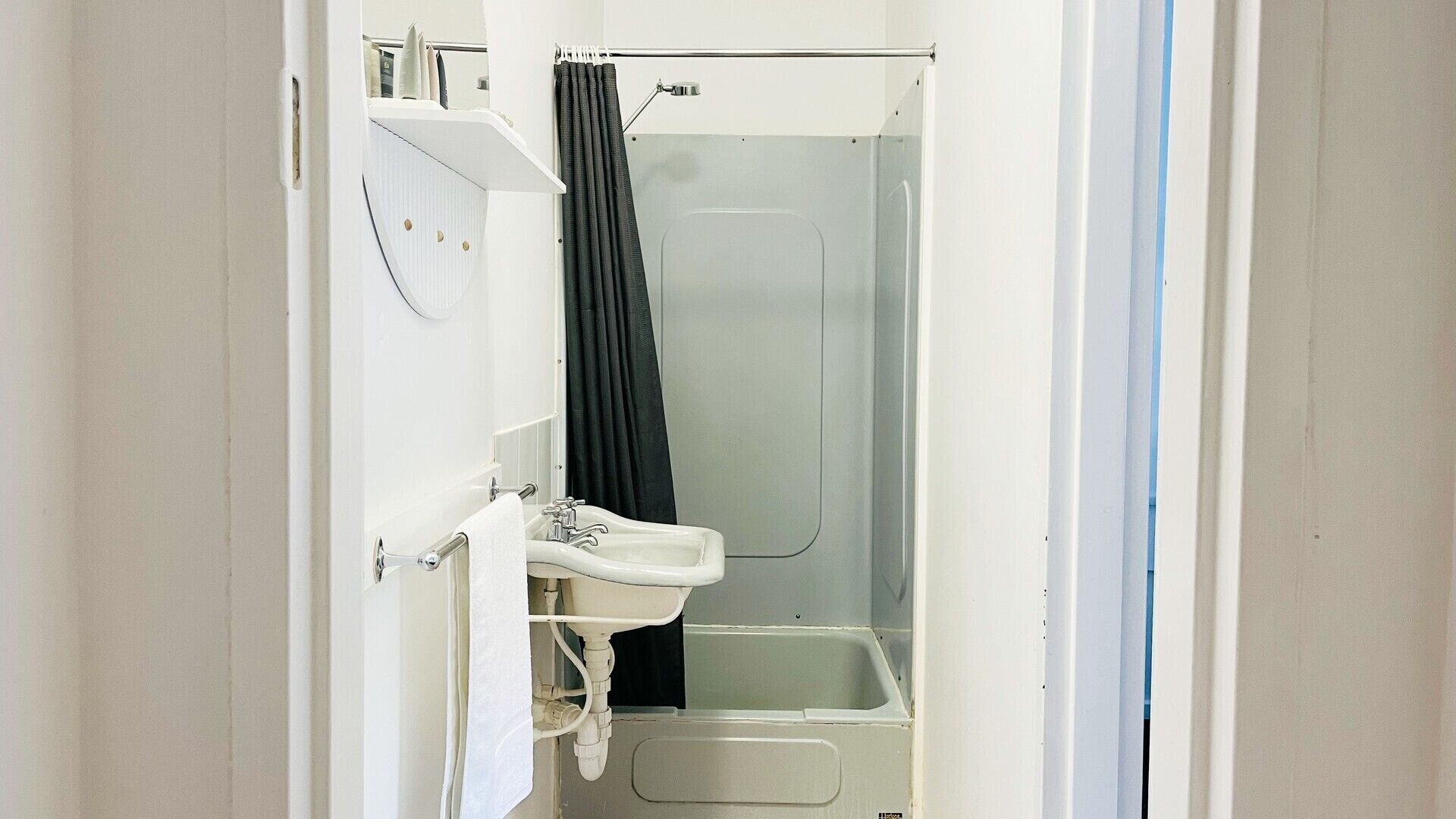 Un baño pequeño con un lavamanos blanco, un espejo y una cabina de ducha.