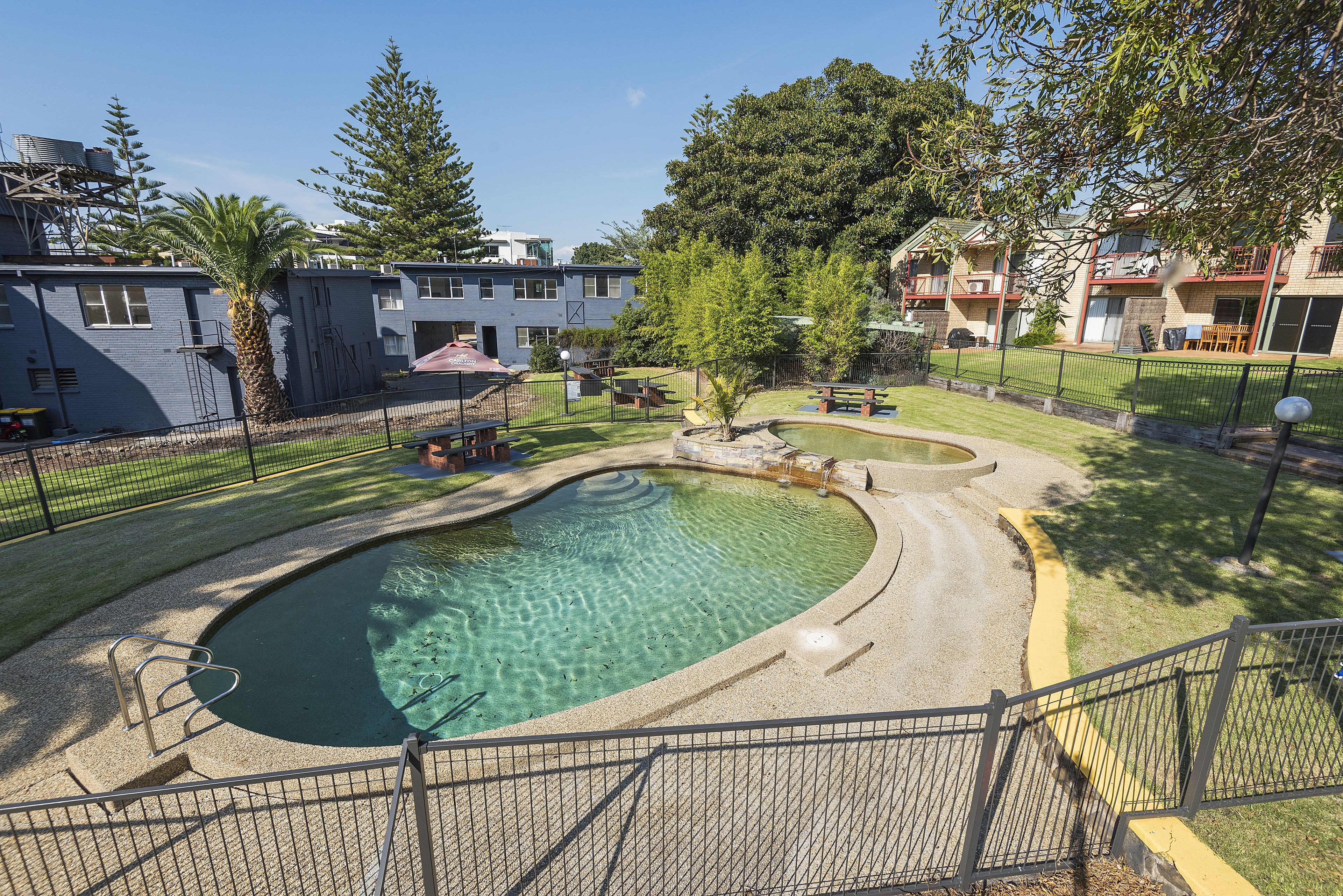Zona residencial con piscina, patio cercado y edificios de apartamentos.