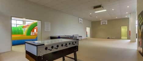 An indoor recreational area with a foosball table and a colorful inflatable play structure.