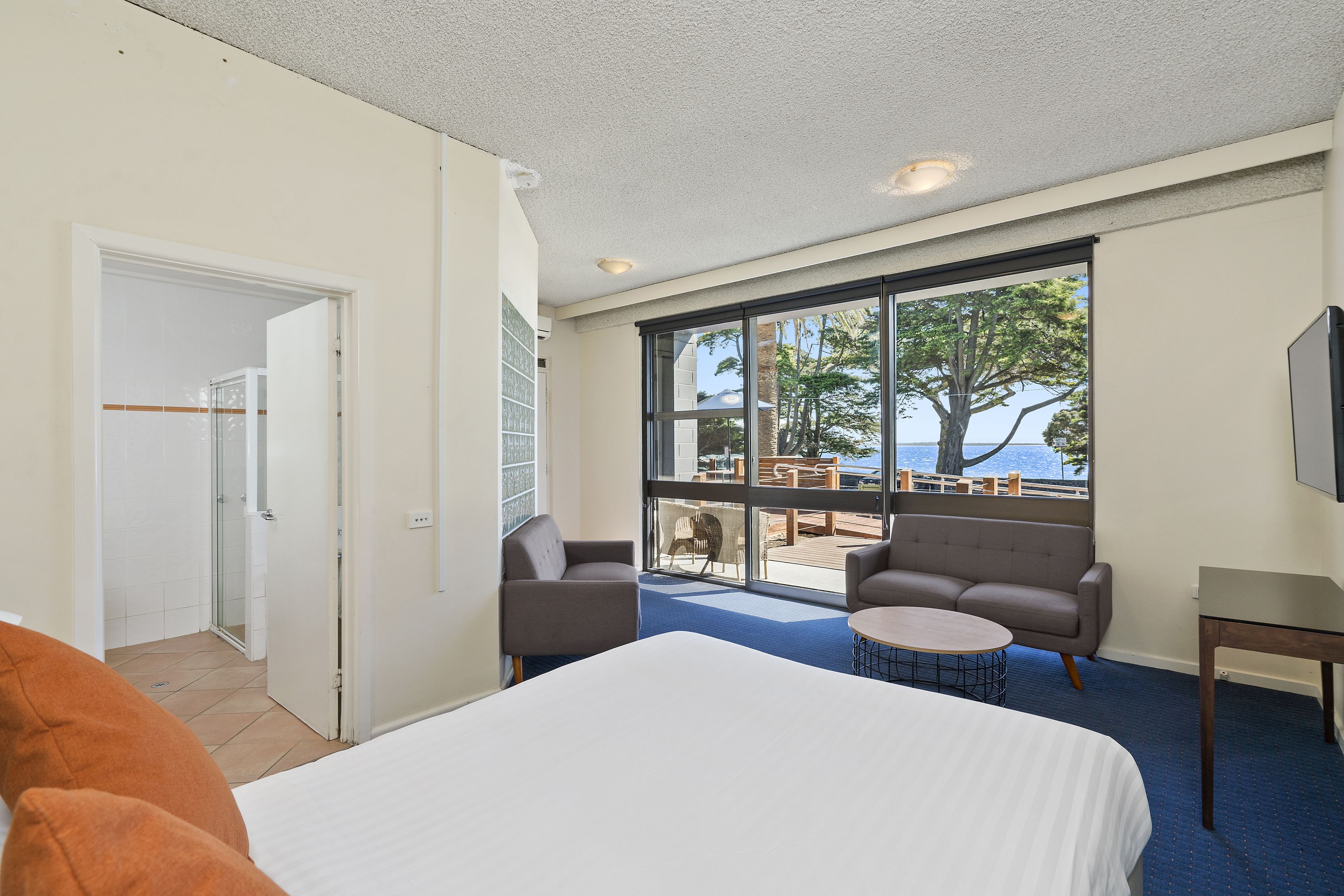 Habitación de hotel con una cama, dos sillones, una mesita redonda y un ventanal con vistas al exterior.