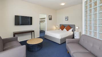 Habitación de hotel con cama, dos sillones, una mesita redonda, televisor y ventana con vista decorativa.