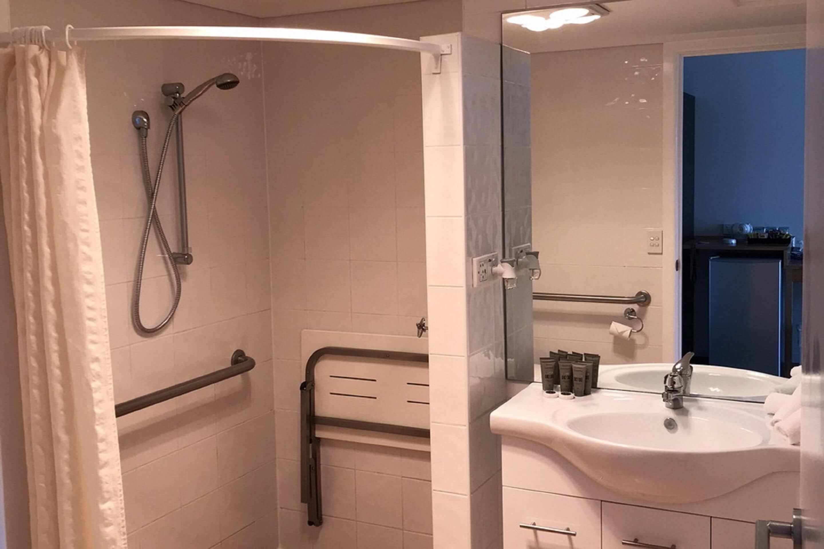Un baño con ducha, lavamanos y espejo.