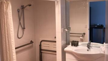 A bathroom with a shower, a sink, and a mirror.