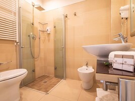 Ein modernes Badezimmer mit einer Duschkabine, einem Bidet und einem großzügigen Waschbecken mit Handtuchhalter.