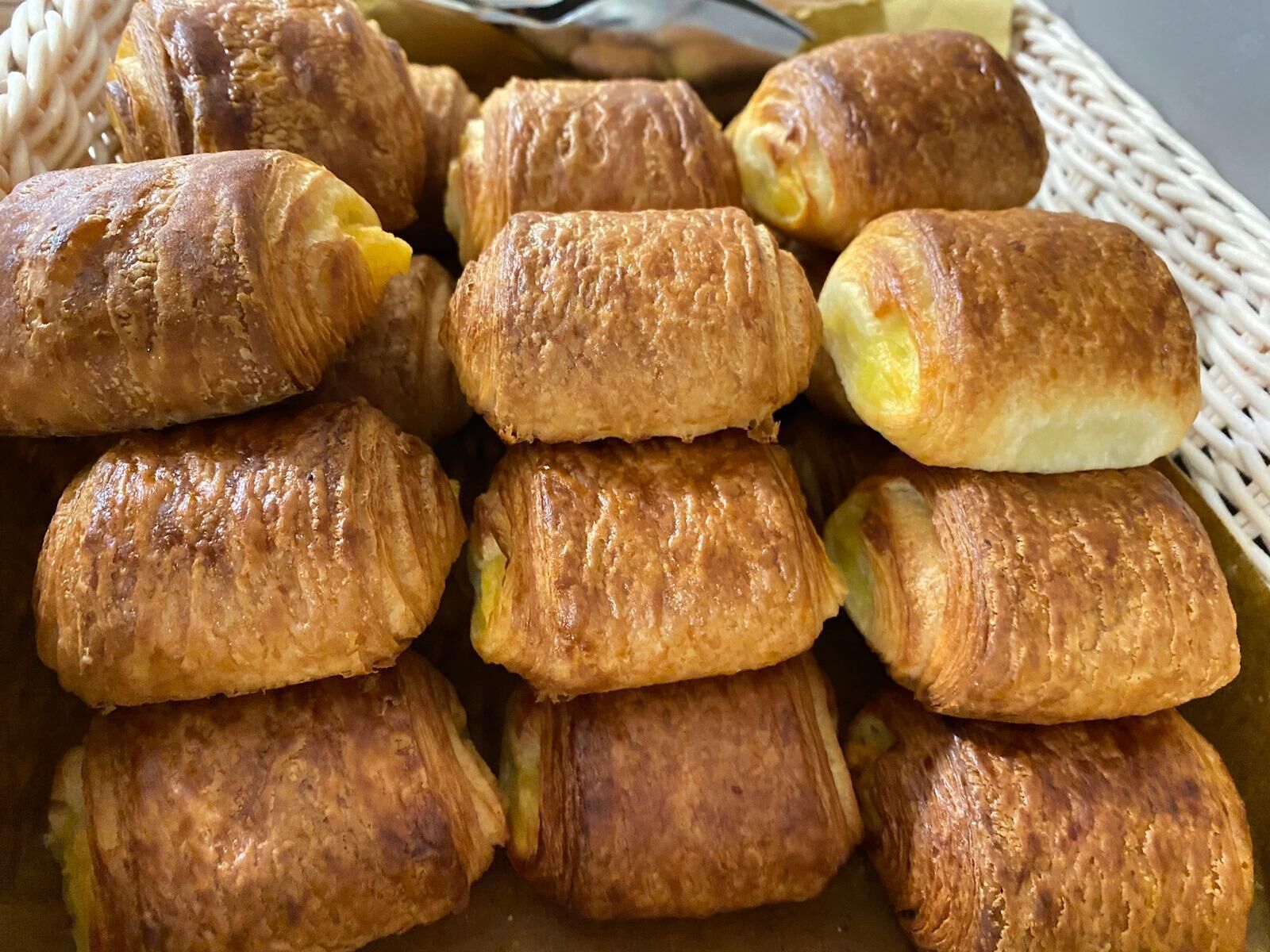 Ein Korb mit goldbraunen Backwaren, vermutlich Croissants, ordentlich angeordnet.