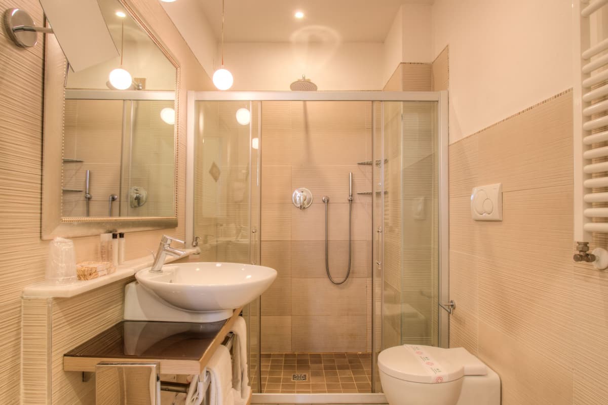 Un baño moderno con ducha de vidrio, dos lavamanos y un inodoro.