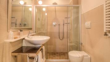 A modern bathroom with a glass-enclosed shower, two sinks, and a toilet.