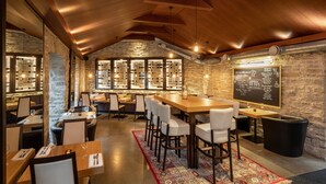 A restaurant with a high ceiling, stone walls, and a large wooden table with chairs. There are multiple hanging light fixtures and a chalkboard menu on the wall. - The von Stackelberg Hotel Tallinn (Tallinn)