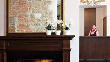A reception area with a fireplace, potted plants, and a chandelier.