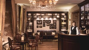 A bar area with a chandelier, bookshelves, a sofa, and a counter. - The von Stackelberg Hotel Tallinn (Tallinn)