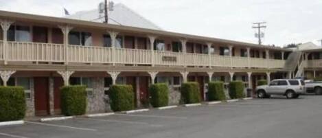 Motel amb una fila de habitacions, una zona de pàrquing coberta i un camió aparcat a l'exterior.