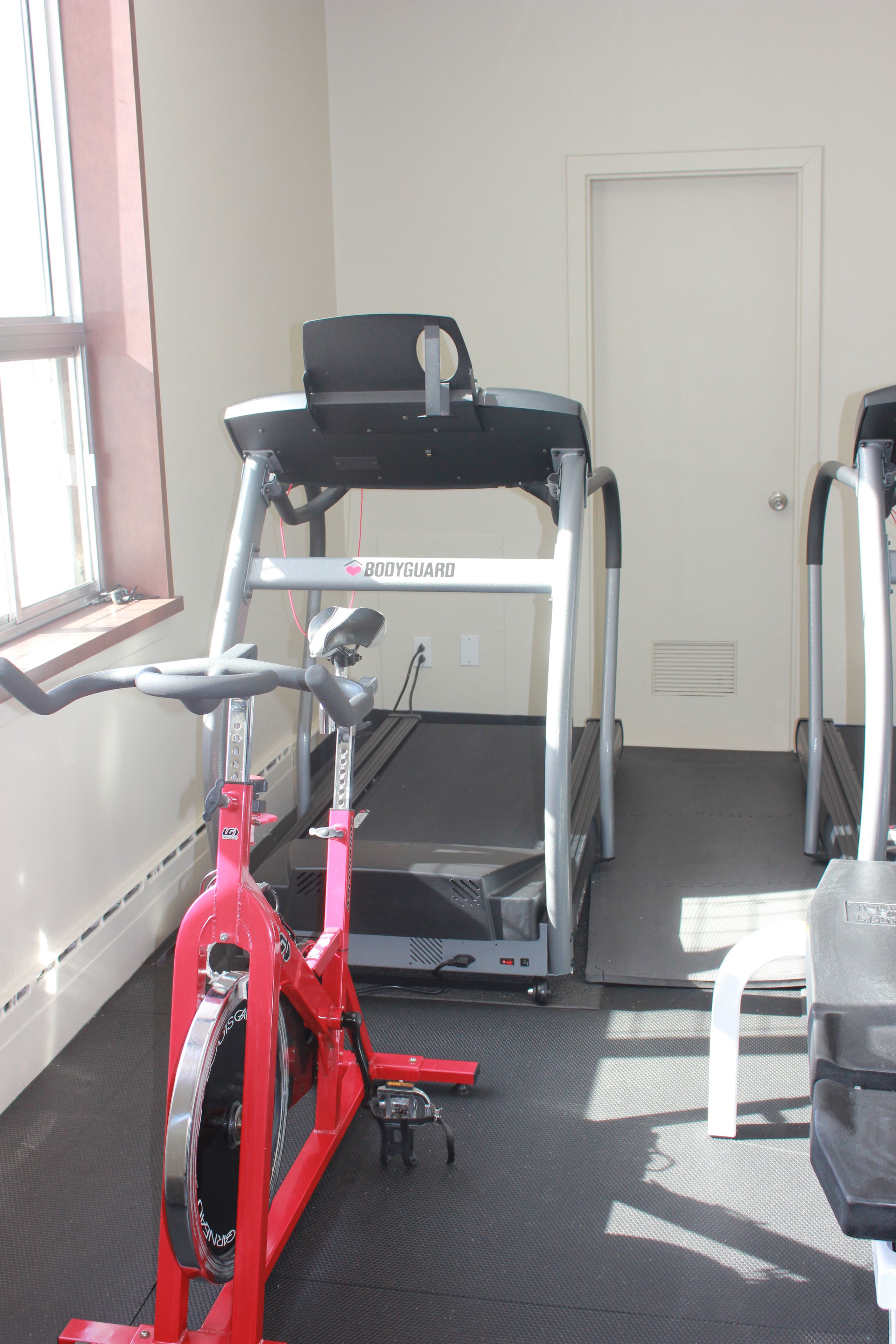 A gym with treadmills, a stationary bike, and a door.