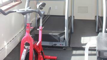 A gym with treadmills, a stationary bike, and a door.