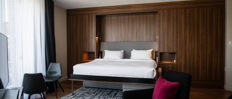 Una habitación de hotel moderna con una cama grande, un escritorio y una silla.