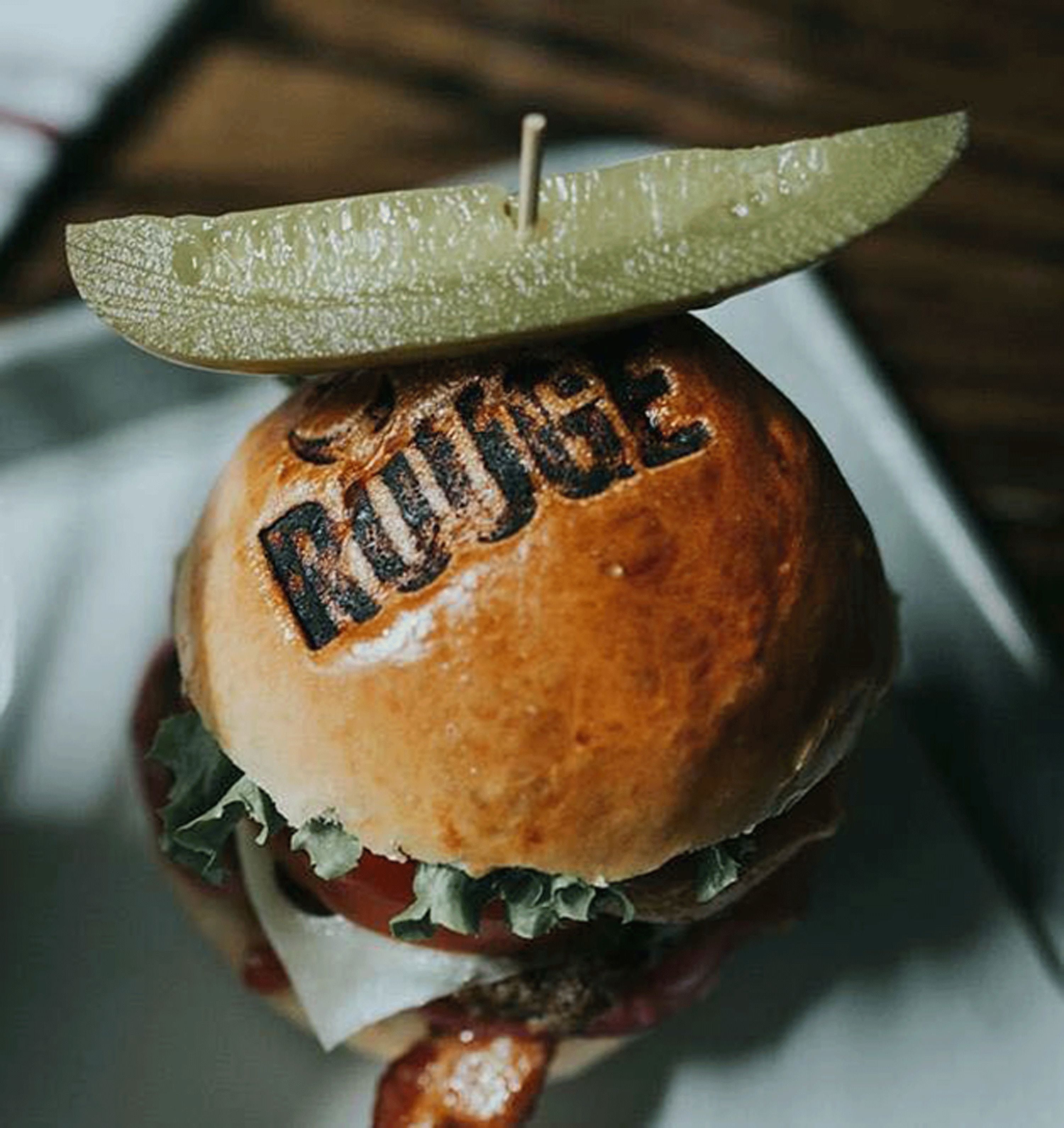 Um hambúrguer com um picles por cima e a palavra "Ridge" no pão.