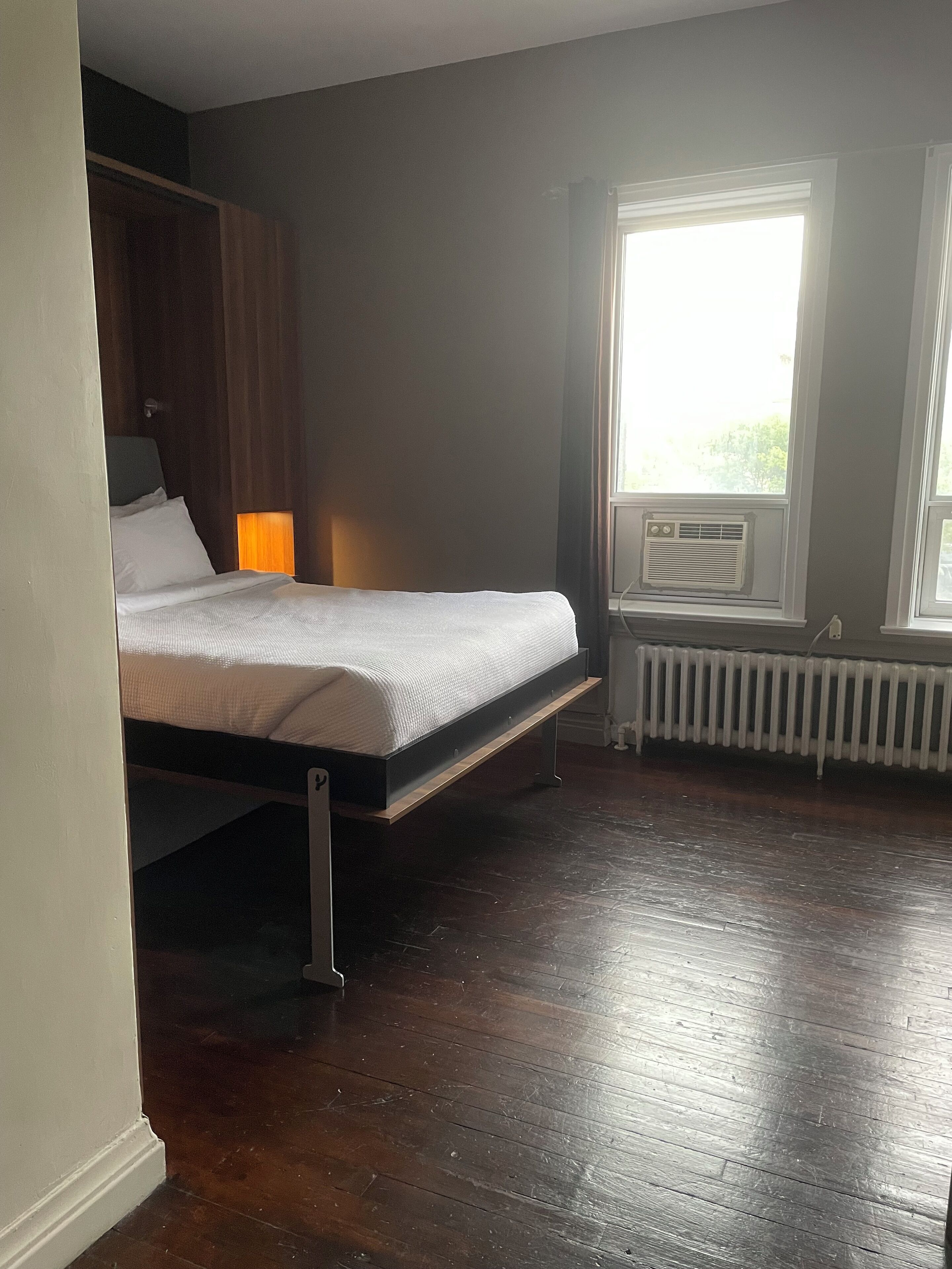 A bedroom with a bed, a radiator, and a window.